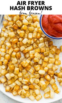 air fryer hash browns on a white plate with ketchup in the background