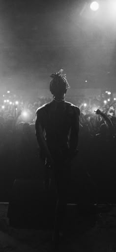 a man standing in front of a crowd at a concert with his back to the camera