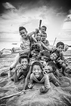 a group of children are posing for a photo on the beach with baseball bats in their hands