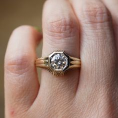 a close up of a person's hand holding a ring with a diamond in it