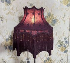 a lamp that is sitting on top of a wooden stand in front of a floral wallpaper