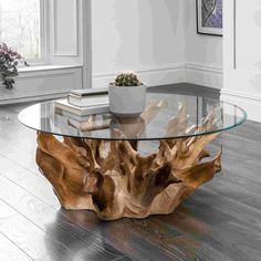 a wooden table with glass top on the floor in front of a potted plant