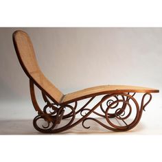 a wooden and wicker chaise lounger with curved legs, designed to look like an intricate scroll