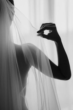 a black and white photo of a woman wearing a veil with her hands on her shoulder