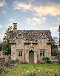 an old brick house with a stone roof and windows on the front lawn is surrounded by green grass