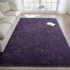 a living room with a purple rug on the floor and a white couch in front of it