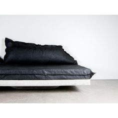 a black and white bed with two pillows on top of it, in front of a wall