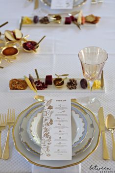 the table is set with gold and white plates, silverware, and place settings