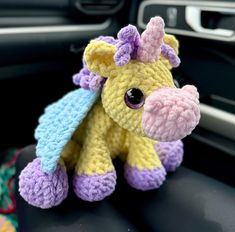 a crocheted stuffed animal sitting on the dashboard of a car