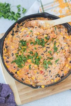 a skillet filled with black beans, corn and cilantro on top of a cutting board