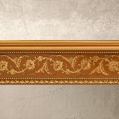 an ornate gold frame with flowers and leaves painted on the wall above it is a vase