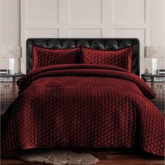 a bed with red bedspread and pillows