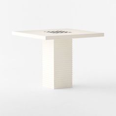 a white square table with an arrow on the top and two lines at the base