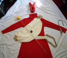 a red and white dress laying on top of a bed next to an orange object