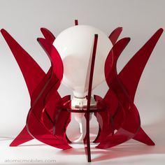 a white and red lamp sitting on top of a glass table next to a light bulb