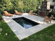 an outdoor pool surrounded by lawn furniture and stone fire place in the middle of a yard