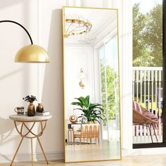 a mirror sitting on top of a wooden floor next to a white table and chair