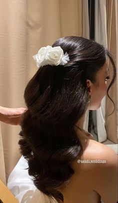 a woman is getting her hair done in front of a mirror with flowers on it