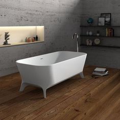 a white bath tub sitting on top of a wooden floor next to a book shelf