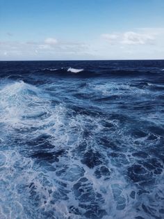 the ocean is blue and choppy with white foamy waves coming in to shore