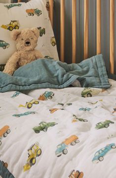 a teddy bear sitting on top of a bed next to pillows and blankets in a child's room