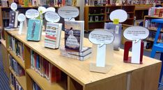 several books are lined up on the shelves in a library with paper speech bubbles attached to them