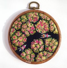 a wooden frame with flowers and birds in it on a white wall behind a key chain