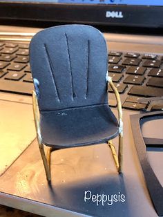 a miniature chair sitting on top of a laptop computer