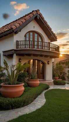 a house with two large planters in front of it and the sun going down