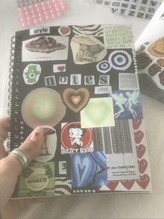 a person is holding a small notebook with stickers and magnets on the pages