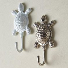 two sea turtle hooks are hanging on the wall next to each other, one is holding a hook