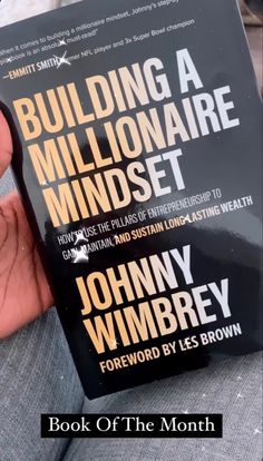 a person holding up a book about building a millionaire mindset