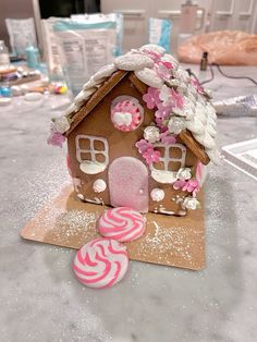 a gingerbread house is decorated with pink and white icing, candies, and marshmallows