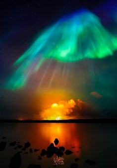 the aurora bore is glowing brightly in the night sky over water with rocks and pebbles