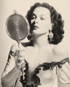 an old photo of a woman holding a mirror