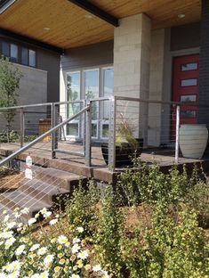 a house with flowers in the foreground and stairs leading up to the front door