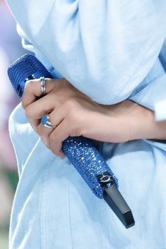 a close up of a person's hand holding a blue umbrella over her shoulder