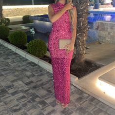 a woman in a pink dress standing next to a palm tree