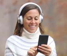 a woman wearing headphones is looking at her phone