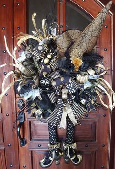 a wreath with black and gold decorations hanging on a wooden door frame in front of a brown door