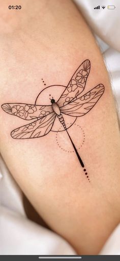 a black and white photo of a tattoo with a dragonfly on it's arm