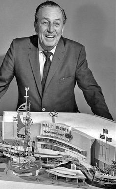 a man in a suit and tie standing next to a model of walt's stadium