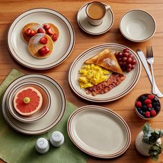 a table topped with plates and cups filled with breakfast foods next to utensils