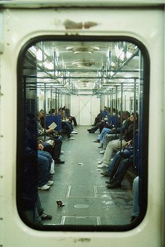 the inside of a subway car with lots of people sitting on it's seats