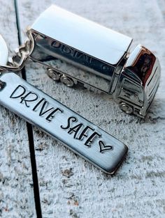 two silver key chains with the words drive safe written on them, sitting next to each other