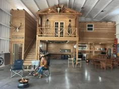 a woman sitting on a chair in front of a wooden house with loft above it