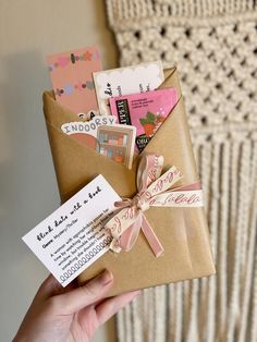 a person holding a brown envelope with a pink ribbon and some cards in it that say goodbye