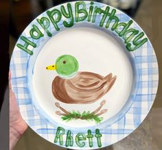 a hand holding a paper plate with a drawing of a duck on it that says happy birthday