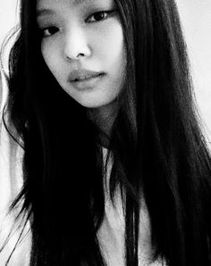 a black and white photo of a woman with long hair looking at the camera,