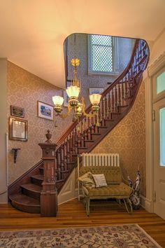 the stairs are made of wood and have chandeliers hanging from them, along with a bench